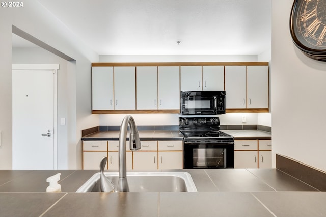 kitchen with white cabinetry, sink, and black appliances