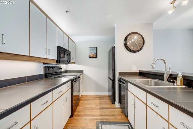 kitchen with white cabinetry, sink, and black appliances