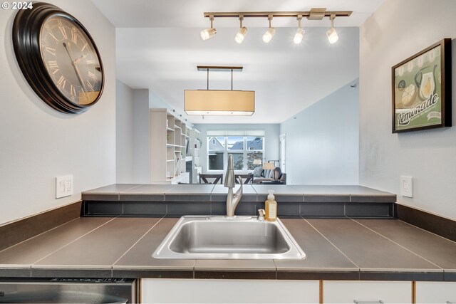 kitchen featuring white cabinetry, dishwasher, decorative light fixtures, and sink