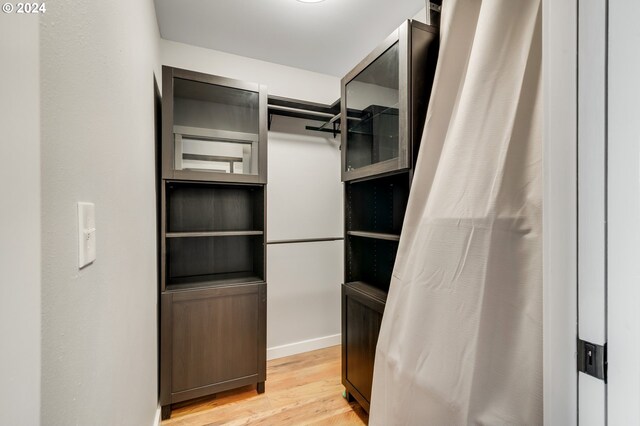 walk in closet with light hardwood / wood-style flooring