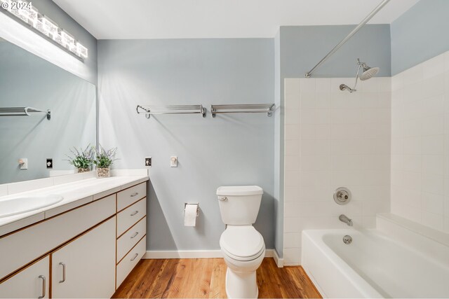 full bathroom featuring tiled shower / bath combo, vanity, hardwood / wood-style flooring, and toilet