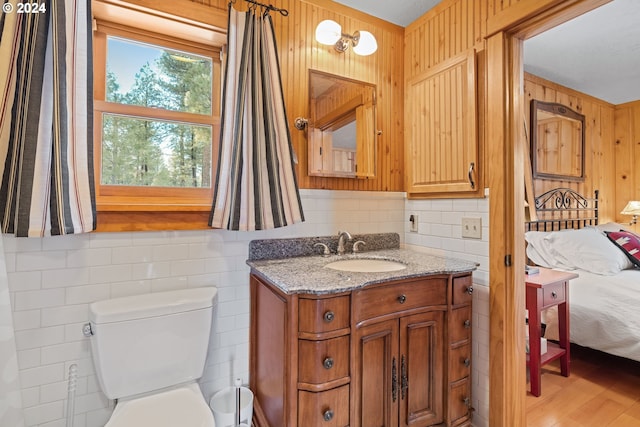 bathroom with hardwood / wood-style floors, vanity, toilet, and wood walls