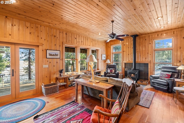 living room featuring a wood stove, wood walls, wooden ceiling, and light hardwood / wood-style floors