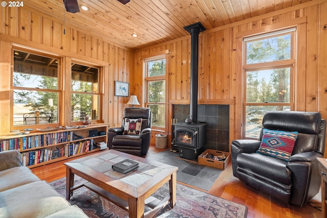 living room featuring a wood stove, wood walls, wooden ceiling, and hardwood / wood-style flooring