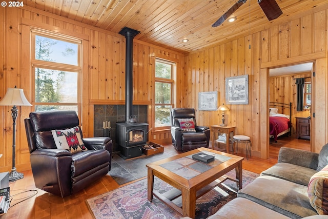 living room featuring wooden ceiling, a wood stove, a wealth of natural light, and wooden walls