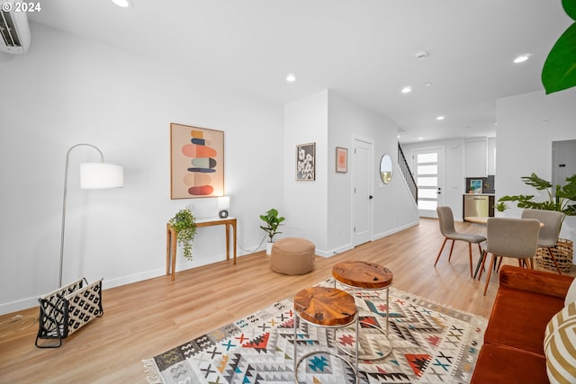 living room with light hardwood / wood-style floors and an AC wall unit