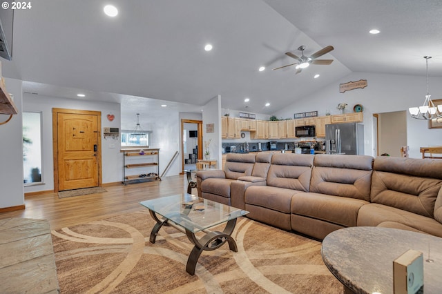 living room featuring high vaulted ceiling, ceiling fan with notable chandelier, and light wood-type flooring