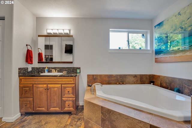 bathroom with vanity and tiled bath