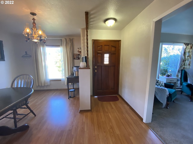 foyer with wood-type flooring, a textured ceiling, and a chandelier