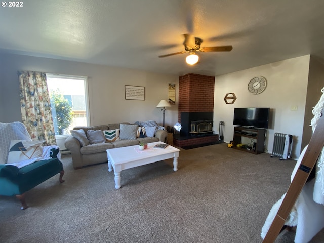 carpeted living room with ceiling fan, a wood stove, and radiator