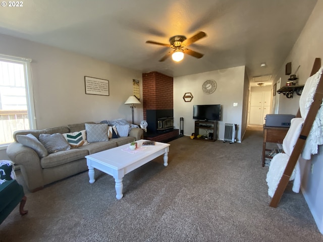 living room with carpet flooring, a wood stove, ceiling fan, and radiator