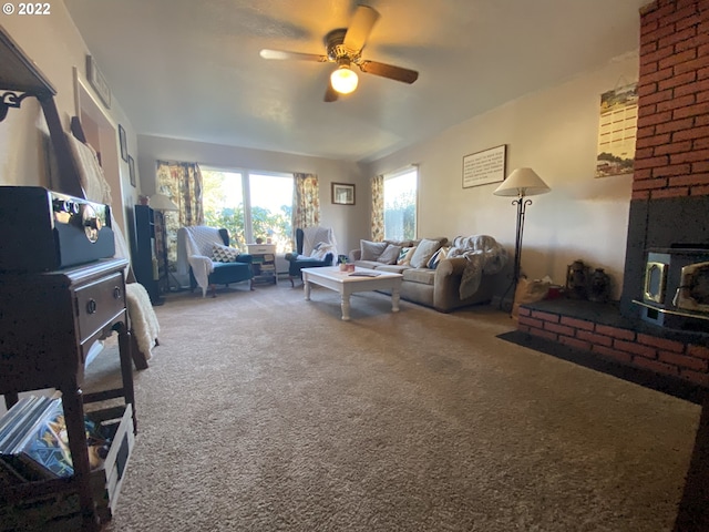 living room featuring ceiling fan, a wood stove, and carpet floors