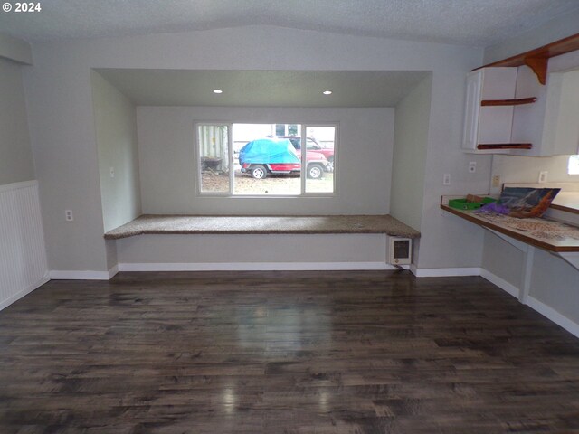 interior space featuring dark hardwood / wood-style flooring, lofted ceiling, and a textured ceiling