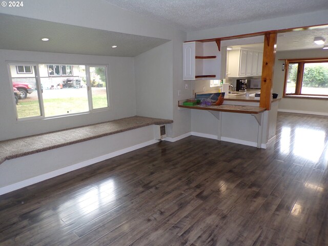 kitchen featuring kitchen peninsula, white cabinetry, dark hardwood / wood-style floors, and a textured ceiling