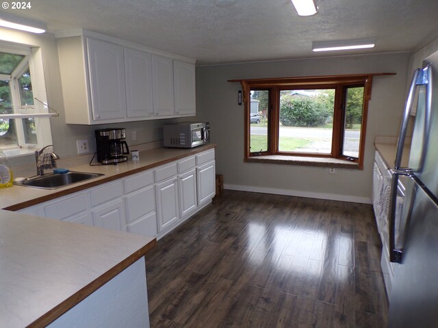 kitchen featuring sink, stainless steel appliances, dark hardwood / wood-style flooring, a textured ceiling, and white cabinets