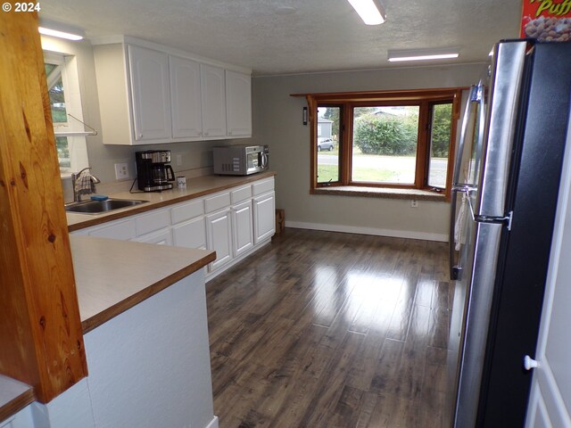 kitchen featuring white cabinetry, sink, stainless steel appliances, dark hardwood / wood-style flooring, and a textured ceiling