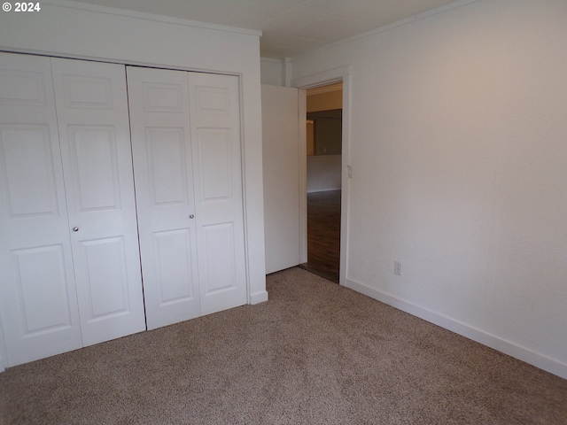 unfurnished bedroom featuring carpet, a closet, and crown molding