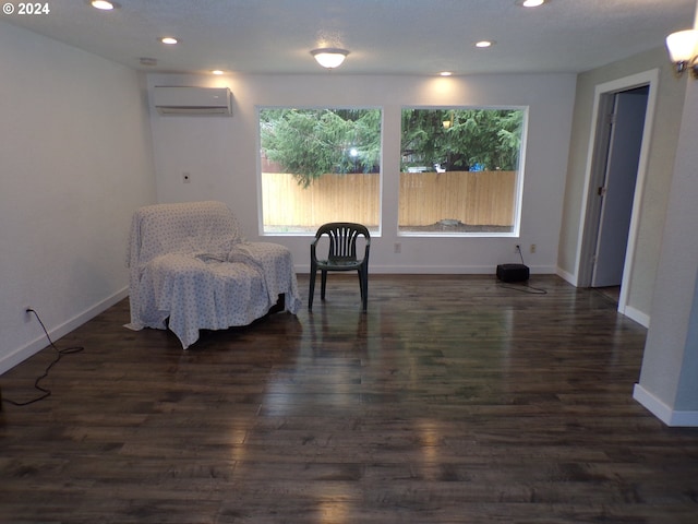 sitting room with a wall unit AC and dark hardwood / wood-style flooring