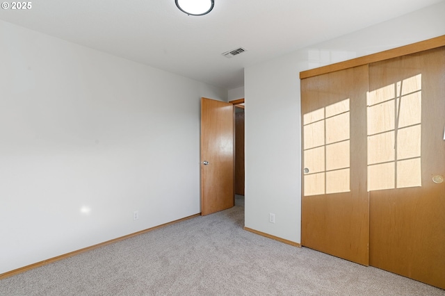 unfurnished bedroom with a closet and light colored carpet