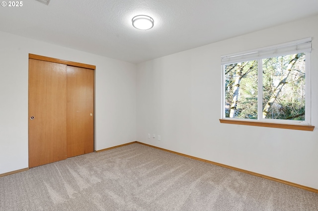 unfurnished bedroom featuring a textured ceiling, a closet, and carpet floors