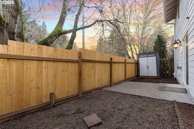 yard at dusk featuring a patio area and a storage shed