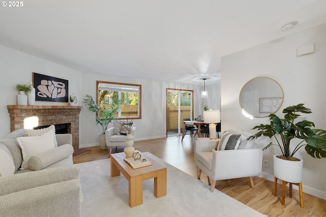 living room featuring a brick fireplace and light wood-type flooring