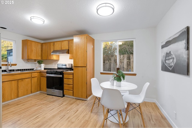 kitchen with sink, light hardwood / wood-style flooring, stainless steel range with gas cooktop, and a textured ceiling