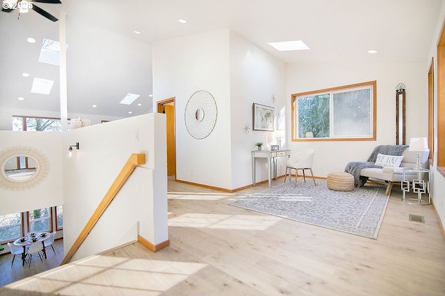 entryway with light wood-type flooring, a skylight, and high vaulted ceiling