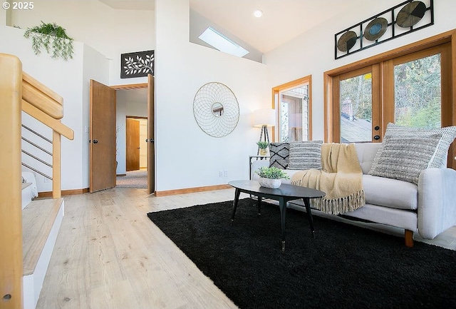 living room featuring light wood-type flooring, vaulted ceiling, and french doors