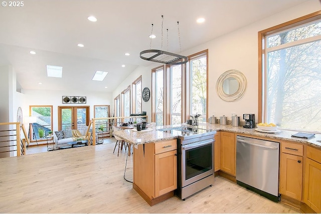 kitchen with light stone countertops, stainless steel appliances, french doors, plenty of natural light, and kitchen peninsula