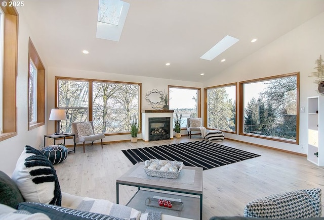 living room with light wood-type flooring, a skylight, plenty of natural light, and high vaulted ceiling