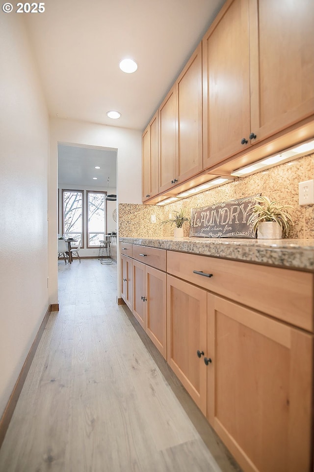 kitchen with decorative backsplash, light hardwood / wood-style floors, and light brown cabinets