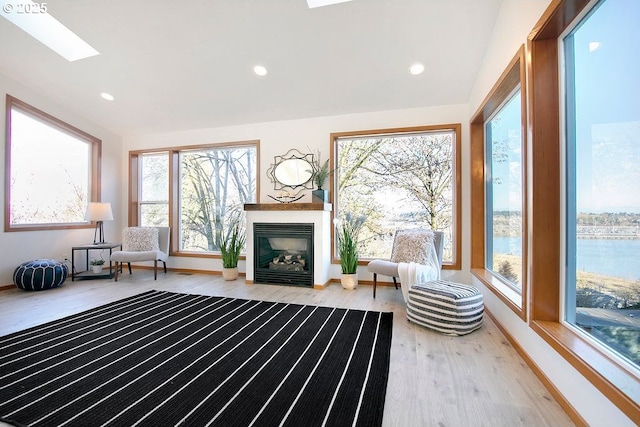 unfurnished room featuring vaulted ceiling with skylight and hardwood / wood-style flooring