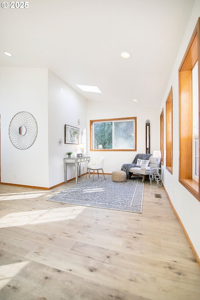 unfurnished room with vaulted ceiling with skylight and light wood-type flooring