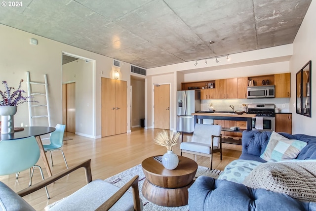 living room with sink, light hardwood / wood-style flooring, and rail lighting