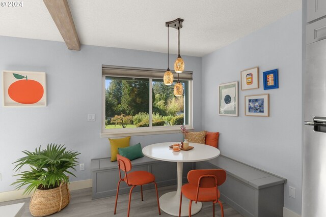 dining area with beamed ceiling, hardwood / wood-style floors, breakfast area, and a textured ceiling