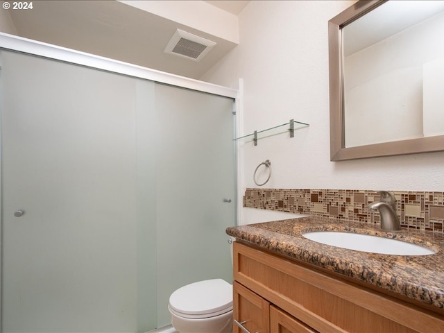 bathroom featuring toilet, decorative backsplash, an enclosed shower, and vanity