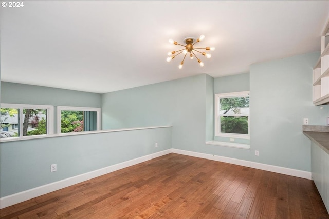 spare room with hardwood / wood-style flooring and a chandelier