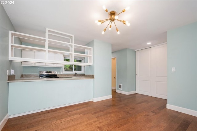 kitchen with stainless steel electric stove, extractor fan, wood-type flooring, an inviting chandelier, and sink