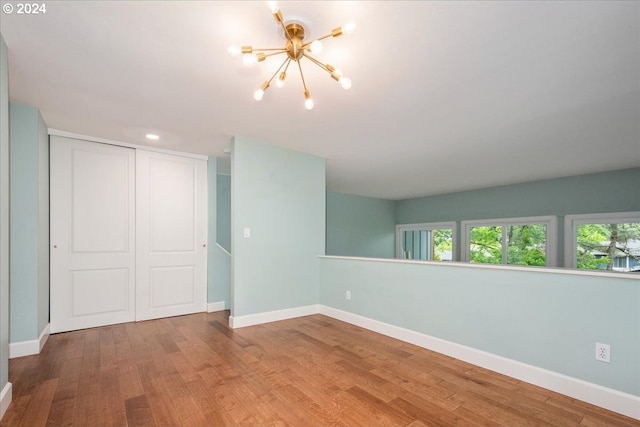 unfurnished room featuring hardwood / wood-style flooring and a chandelier