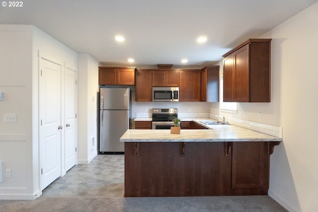 kitchen with appliances with stainless steel finishes, a sink, light countertops, a peninsula, and recessed lighting