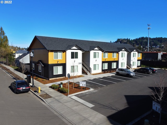 view of building exterior with uncovered parking, stairs, and a residential view