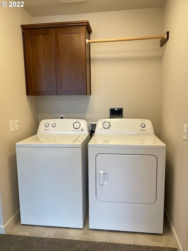 clothes washing area featuring washing machine and clothes dryer and cabinets