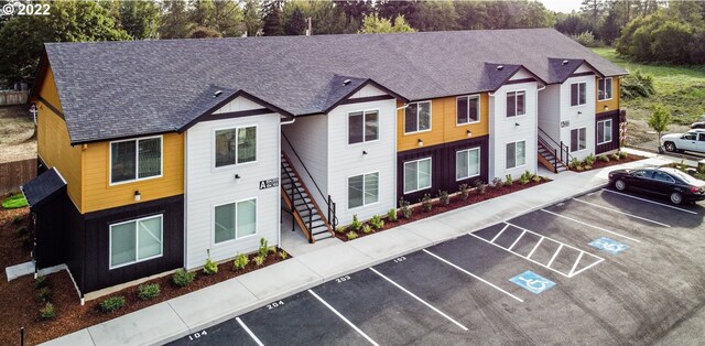 view of building exterior with stairway and uncovered parking