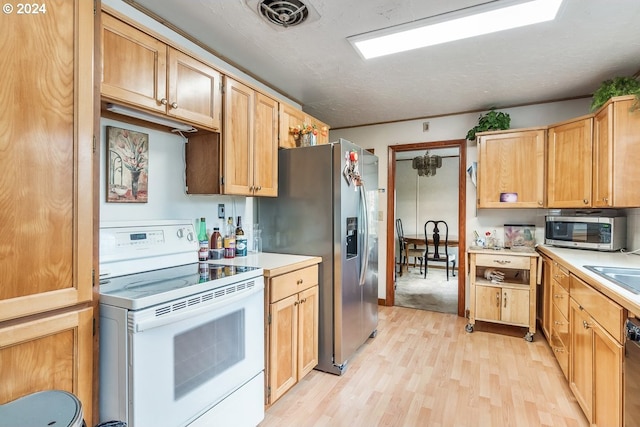 kitchen featuring stainless steel appliances, light hardwood / wood-style floors, and a textured ceiling