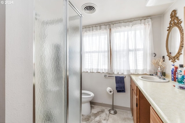 bathroom with vanity, a shower with shower door, toilet, and tile patterned floors