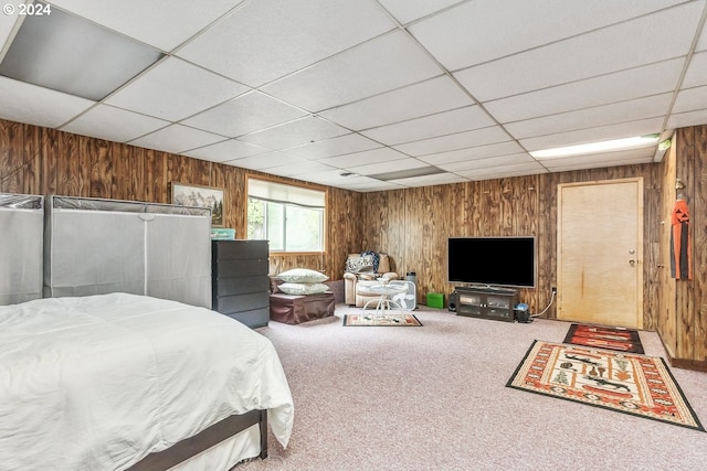 carpeted bedroom featuring wooden walls and a paneled ceiling