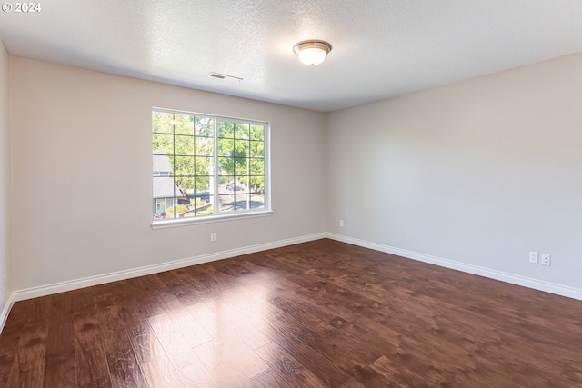 unfurnished room featuring dark wood-type flooring and a textured ceiling