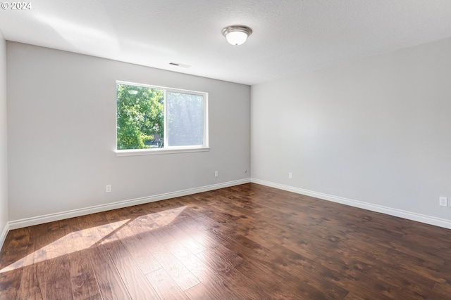 empty room with a textured ceiling and dark wood-type flooring