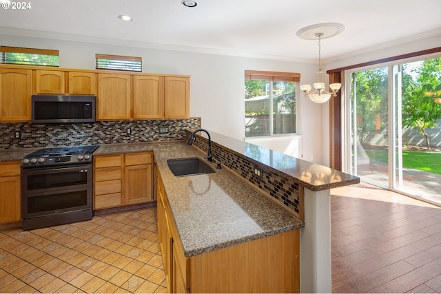 kitchen with sink, an inviting chandelier, pendant lighting, appliances with stainless steel finishes, and ornamental molding